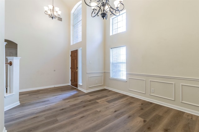 entrance foyer featuring wood-type flooring, a high ceiling, and an inviting chandelier