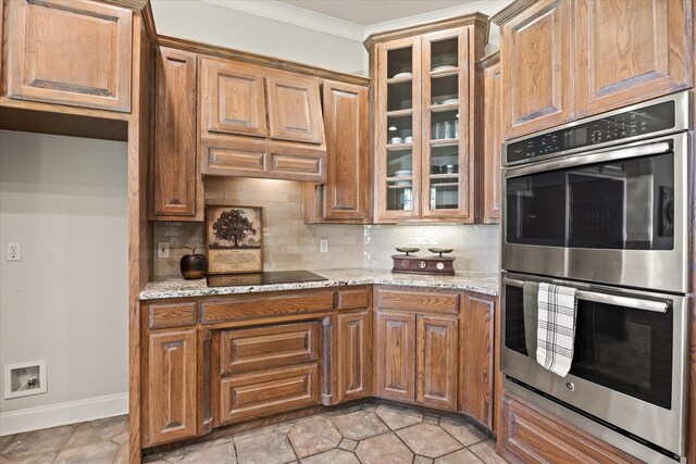 kitchen with tasteful backsplash, light stone countertops, black electric cooktop, and double oven