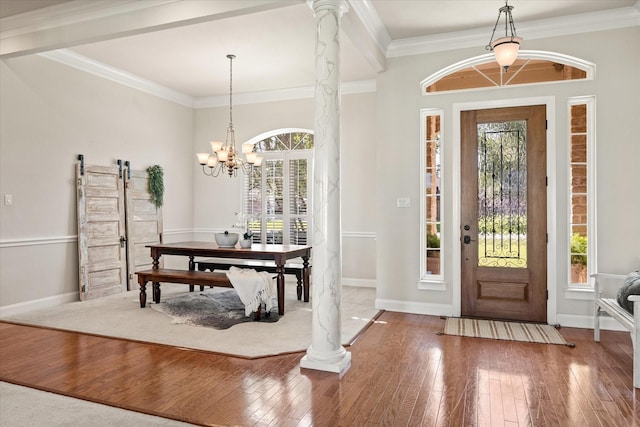 foyer entrance featuring crown molding, wood-type flooring, a barn door, and ornate columns