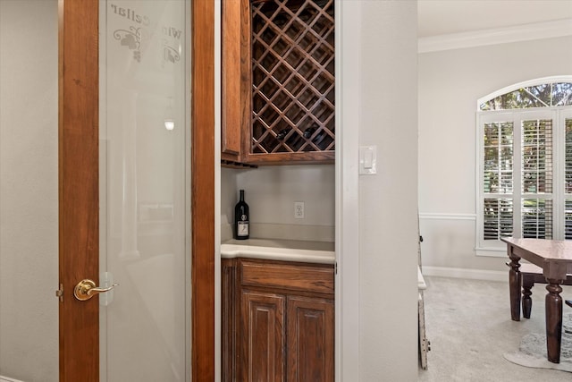 wine area with ornamental molding, light carpet, and bar