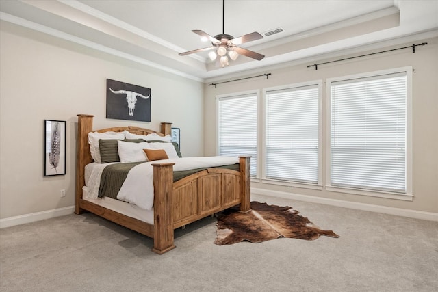 carpeted bedroom with crown molding, ceiling fan, and a tray ceiling