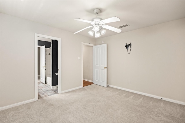 unfurnished bedroom featuring light carpet, ceiling fan, and ensuite bath