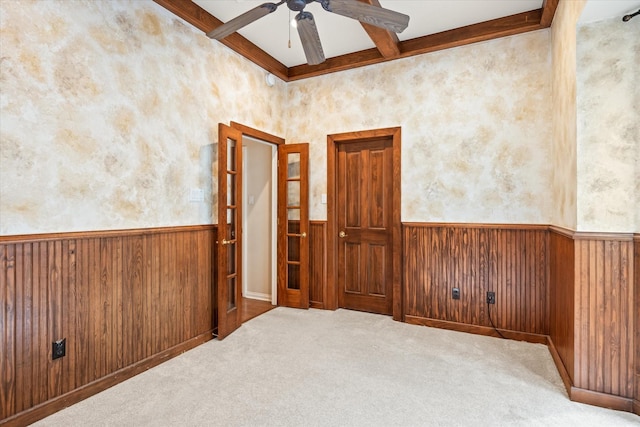 carpeted spare room with coffered ceiling, ceiling fan, beam ceiling, and wood walls