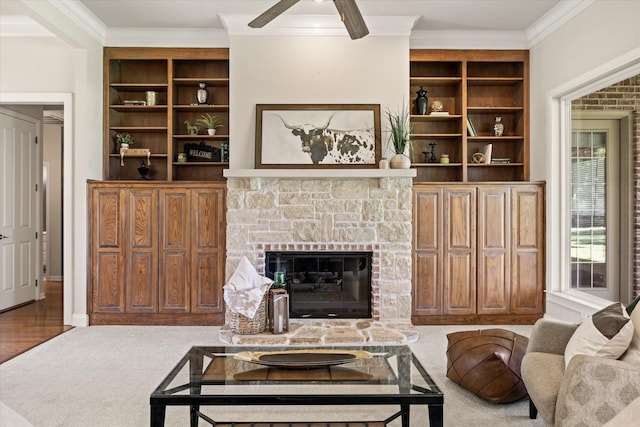 living room with ceiling fan, ornamental molding, a stone fireplace, and built in features