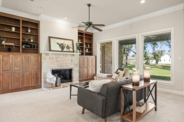 living room with crown molding, ceiling fan, a fireplace, built in shelves, and light colored carpet