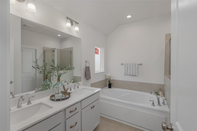 bathroom with plus walk in shower, dual bowl vanity, vaulted ceiling, and tile patterned floors