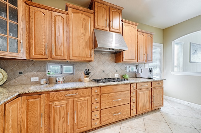 kitchen featuring light stone counters, tasteful backsplash, light tile patterned floors, and stainless steel gas stovetop