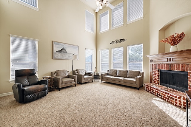 carpeted living room featuring ceiling fan, a fireplace, and a towering ceiling