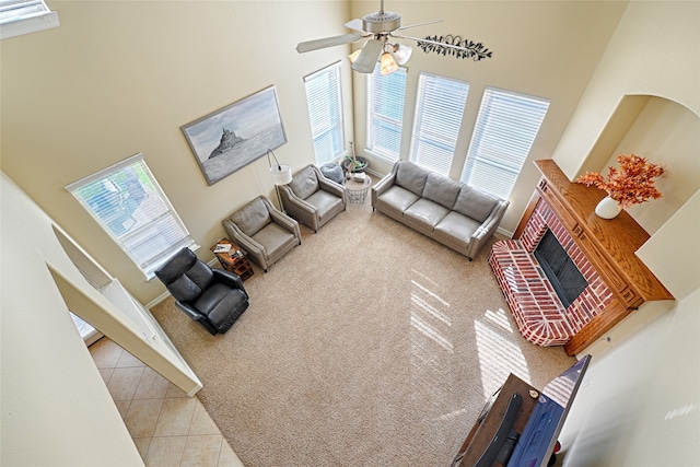 living room with a wealth of natural light, ceiling fan, a towering ceiling, and a fireplace