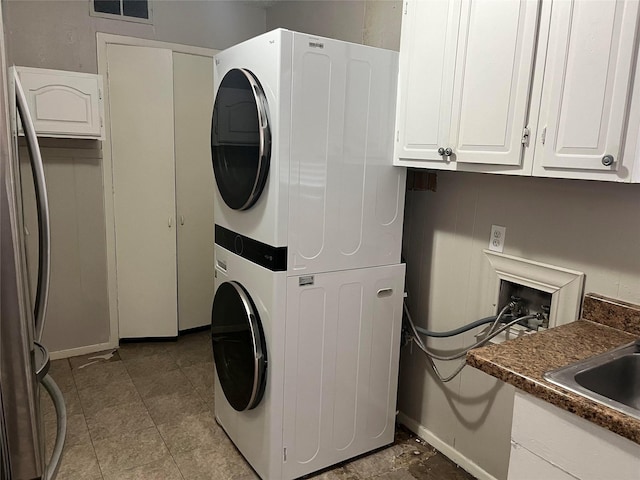 washroom with cabinets and stacked washer / dryer