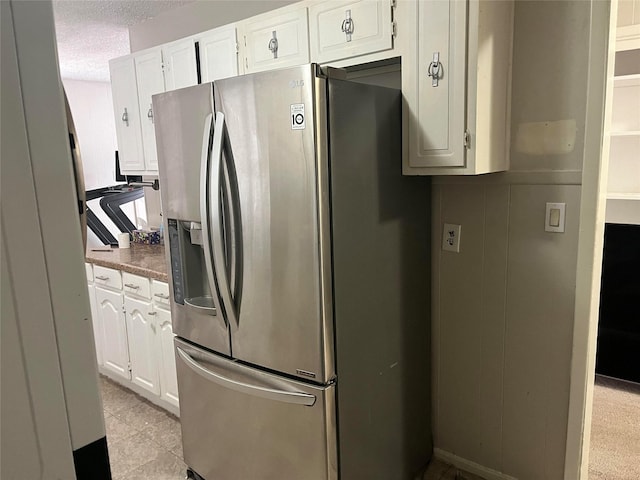 kitchen with stainless steel fridge with ice dispenser, a textured ceiling, and white cabinets