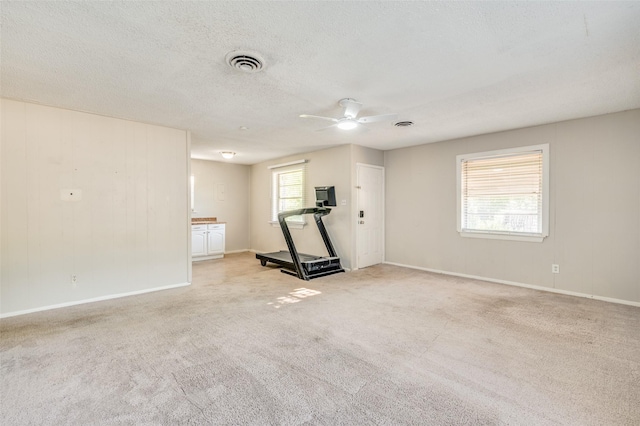 interior space with ceiling fan, light colored carpet, and a textured ceiling