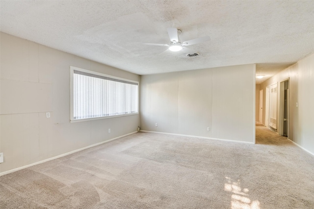 spare room featuring ceiling fan, light colored carpet, and a textured ceiling