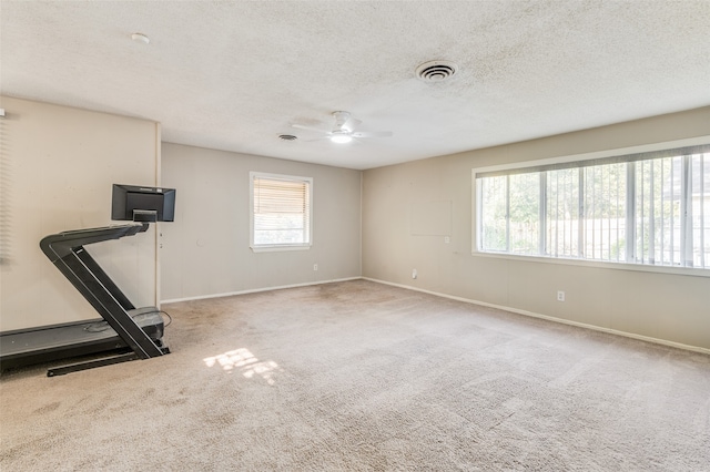 workout area featuring carpet flooring, ceiling fan, and a textured ceiling