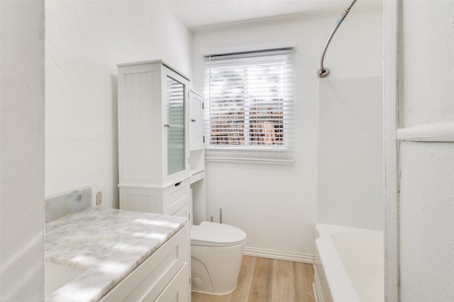 full bathroom featuring a textured ceiling, vanity, toilet,  shower combination, and hardwood / wood-style flooring