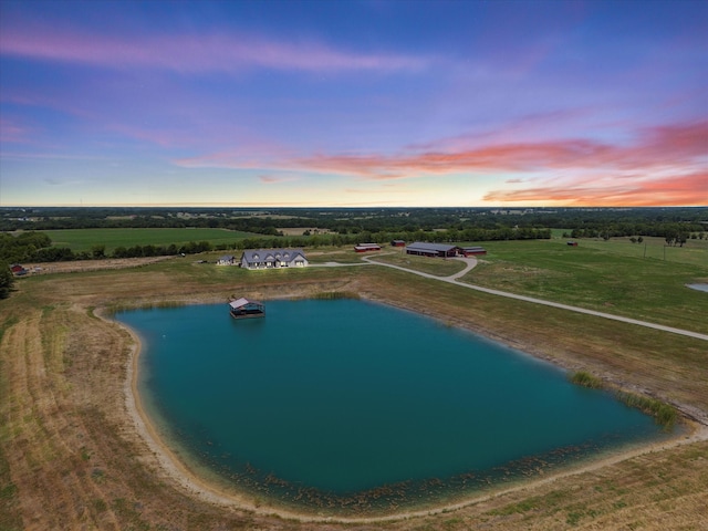 aerial view at dusk featuring a water view and a rural view