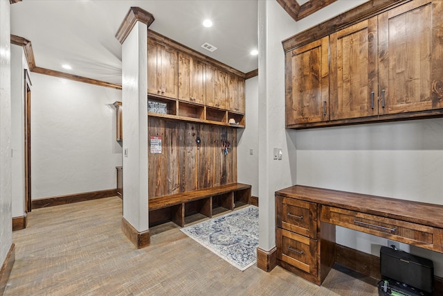 mudroom featuring ornamental molding and built in desk