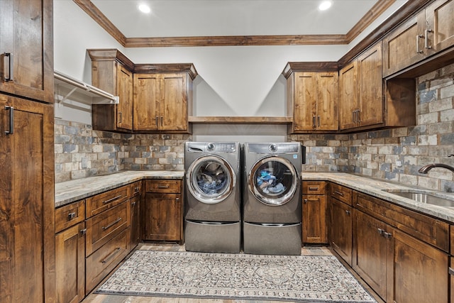 laundry area with sink, cabinets, washing machine and dryer, and ornamental molding