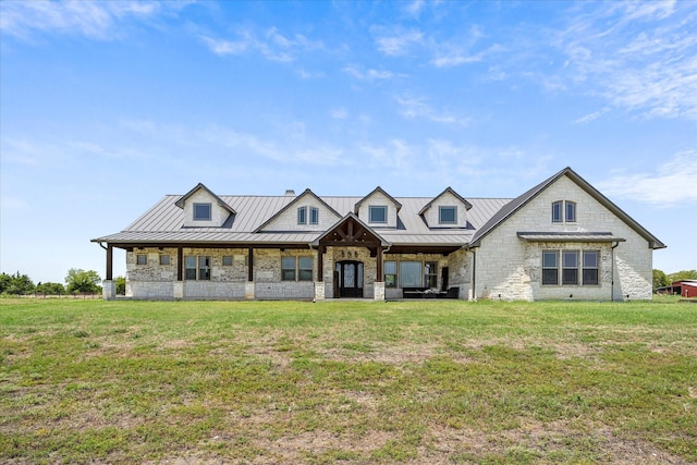 view of front of property featuring a standing seam roof, metal roof, stone siding, and a front lawn