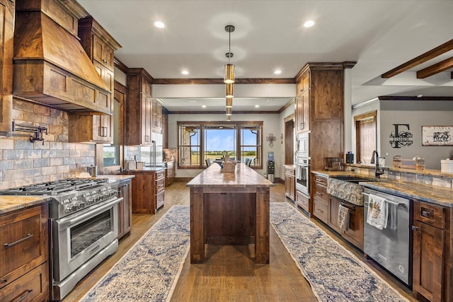 kitchen with custom exhaust hood, a sink, appliances with stainless steel finishes, crown molding, and a kitchen island