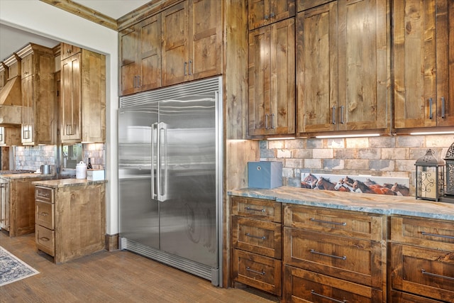 kitchen with dark wood-type flooring, backsplash, and stainless steel built in fridge