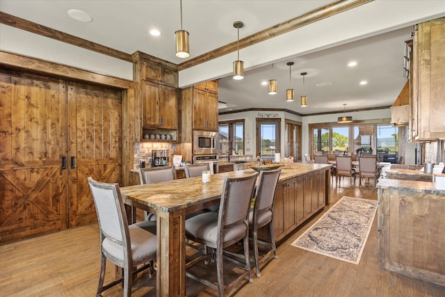 dining area with sink, light hardwood / wood-style flooring, ornamental molding, and wooden walls