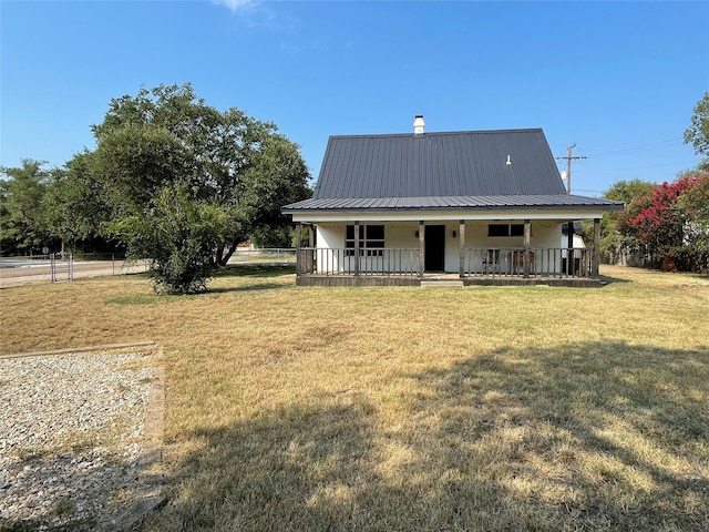 view of front of property with covered porch, metal roof, a front yard, and fence