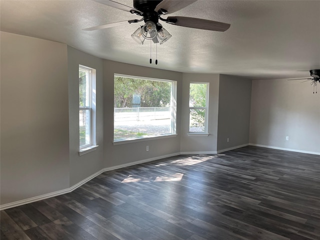 empty room with dark wood-style flooring, plenty of natural light, a textured ceiling, and baseboards