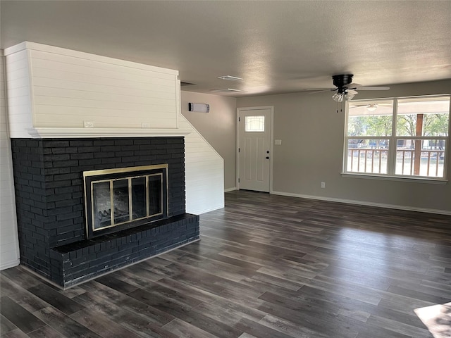 unfurnished living room featuring a textured ceiling, a fireplace, dark wood finished floors, and a healthy amount of sunlight