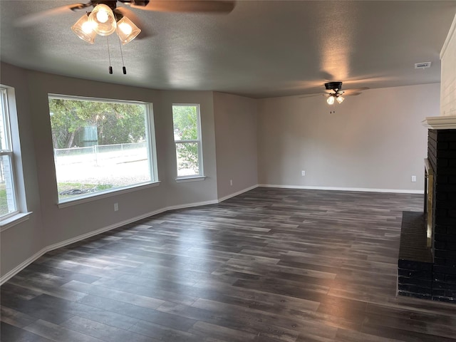 unfurnished living room with a textured ceiling, a fireplace, dark wood finished floors, and visible vents