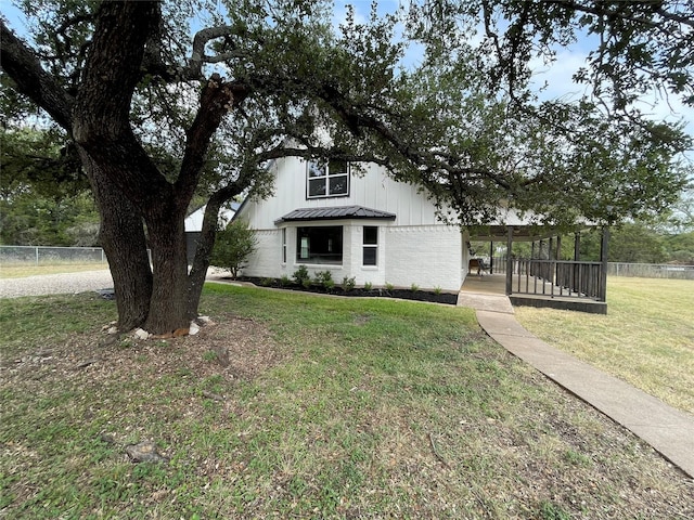 view of front of property featuring a standing seam roof, fence, metal roof, and a front yard