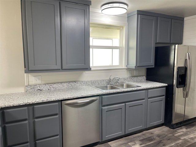 kitchen with dark wood-type flooring, appliances with stainless steel finishes, gray cabinets, and a sink