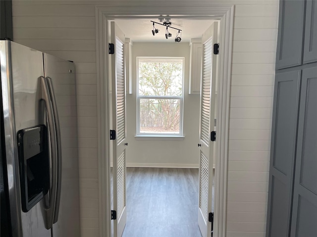 clothes washing area with laundry area, baseboards, independent washer and dryer, rail lighting, and light wood-style floors