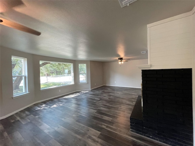 unfurnished living room featuring a textured ceiling, baseboards, dark wood finished floors, and a ceiling fan