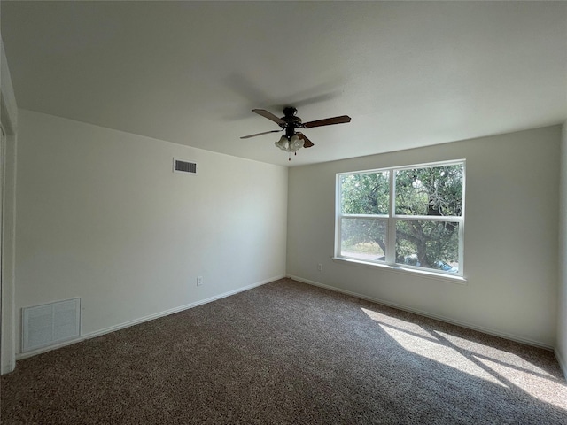 empty room with carpet floors, a ceiling fan, visible vents, and baseboards