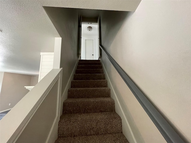 staircase with a textured ceiling