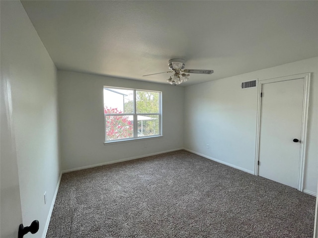 empty room featuring ceiling fan, baseboards, visible vents, and dark colored carpet