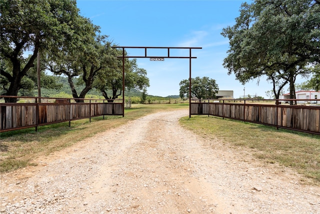 view of street featuring dirt driveway and a gated entry