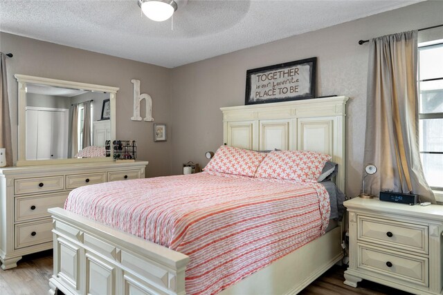 bedroom featuring light hardwood / wood-style flooring, a textured ceiling, and ceiling fan