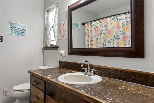 bathroom featuring vanity, a textured ceiling, and toilet