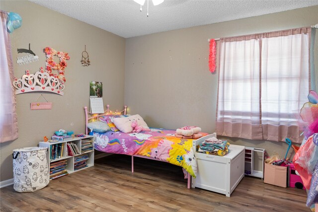 bedroom with a textured ceiling, multiple windows, and hardwood / wood-style floors