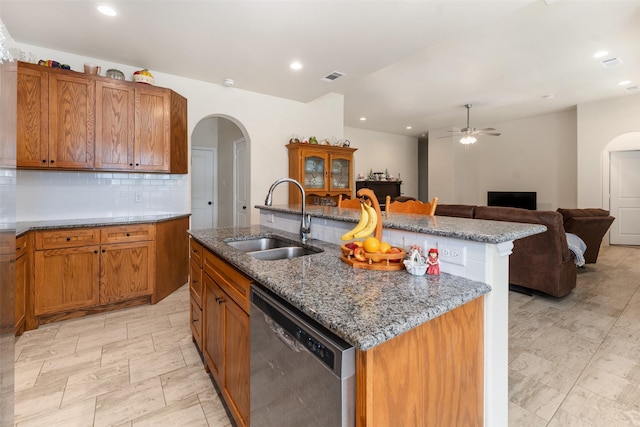 kitchen featuring an island with sink, stainless steel dishwasher, sink, and tasteful backsplash