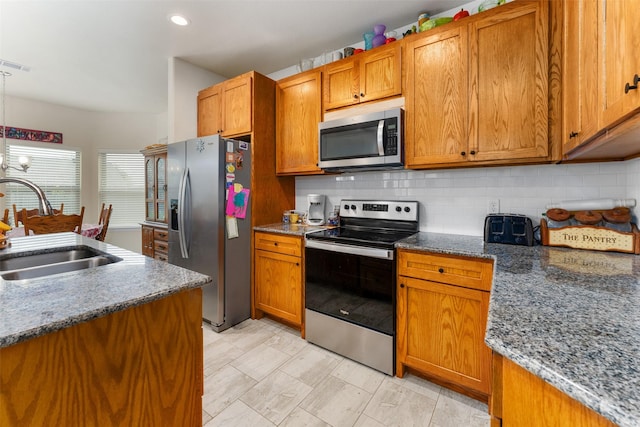 kitchen featuring dark stone countertops, stainless steel appliances, tasteful backsplash, and sink