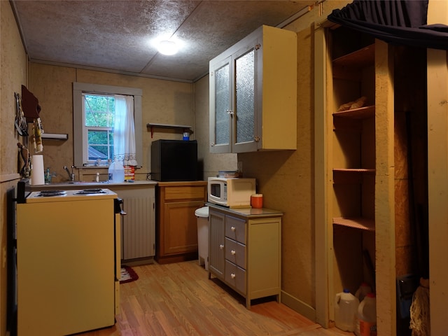 kitchen with white appliances, a textured ceiling, and light wood-type flooring