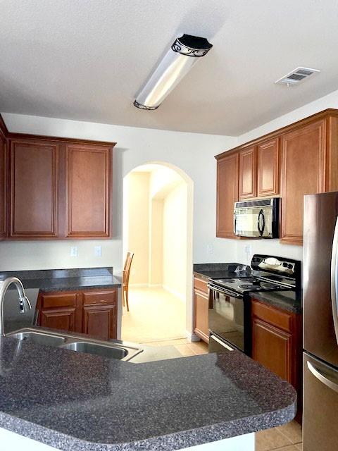 kitchen with sink, light tile patterned floors, and black appliances