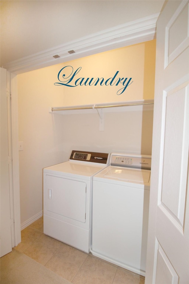 clothes washing area featuring light tile patterned flooring and washer and dryer