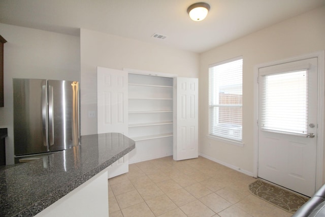 kitchen with light tile patterned floors, plenty of natural light, and stainless steel fridge