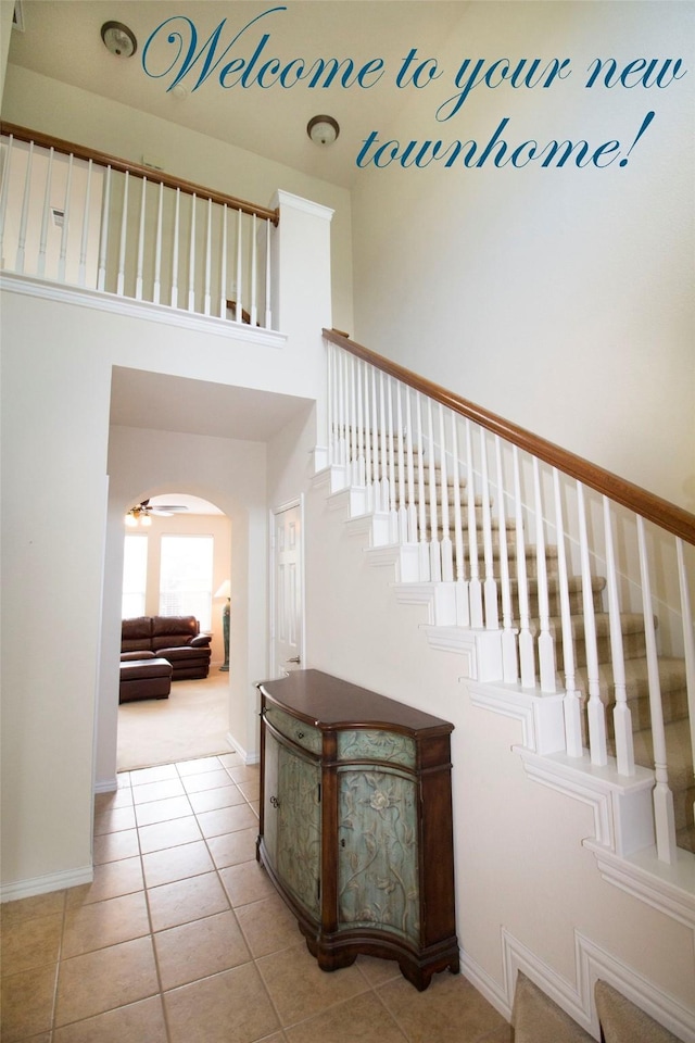 stairs featuring ceiling fan and tile patterned floors