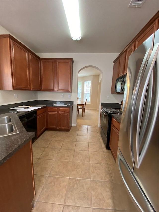 kitchen featuring sink, light tile patterned floors, and black appliances