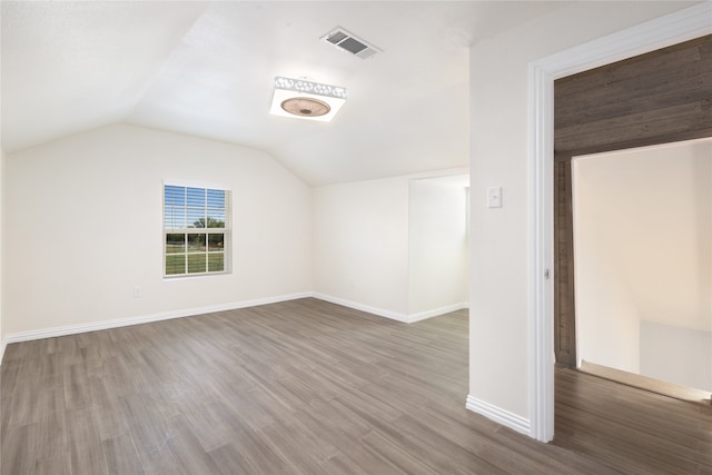 additional living space featuring lofted ceiling, plenty of natural light, and dark hardwood / wood-style flooring